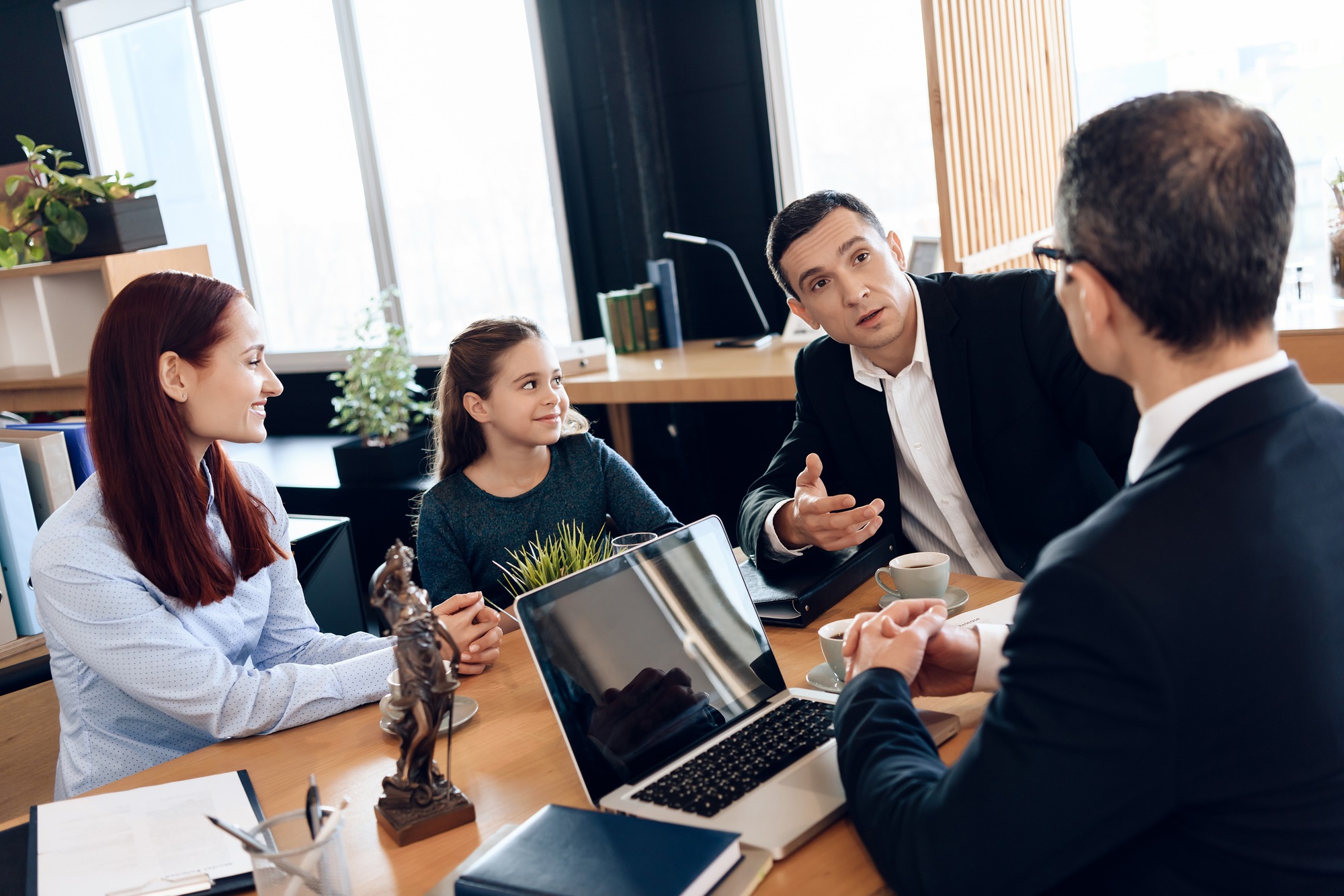 Adult Father, Red Head Mother And Little Smiling Daughter Are Sitting In Lawyer's Office. Family In Office Of Family Lawyer.