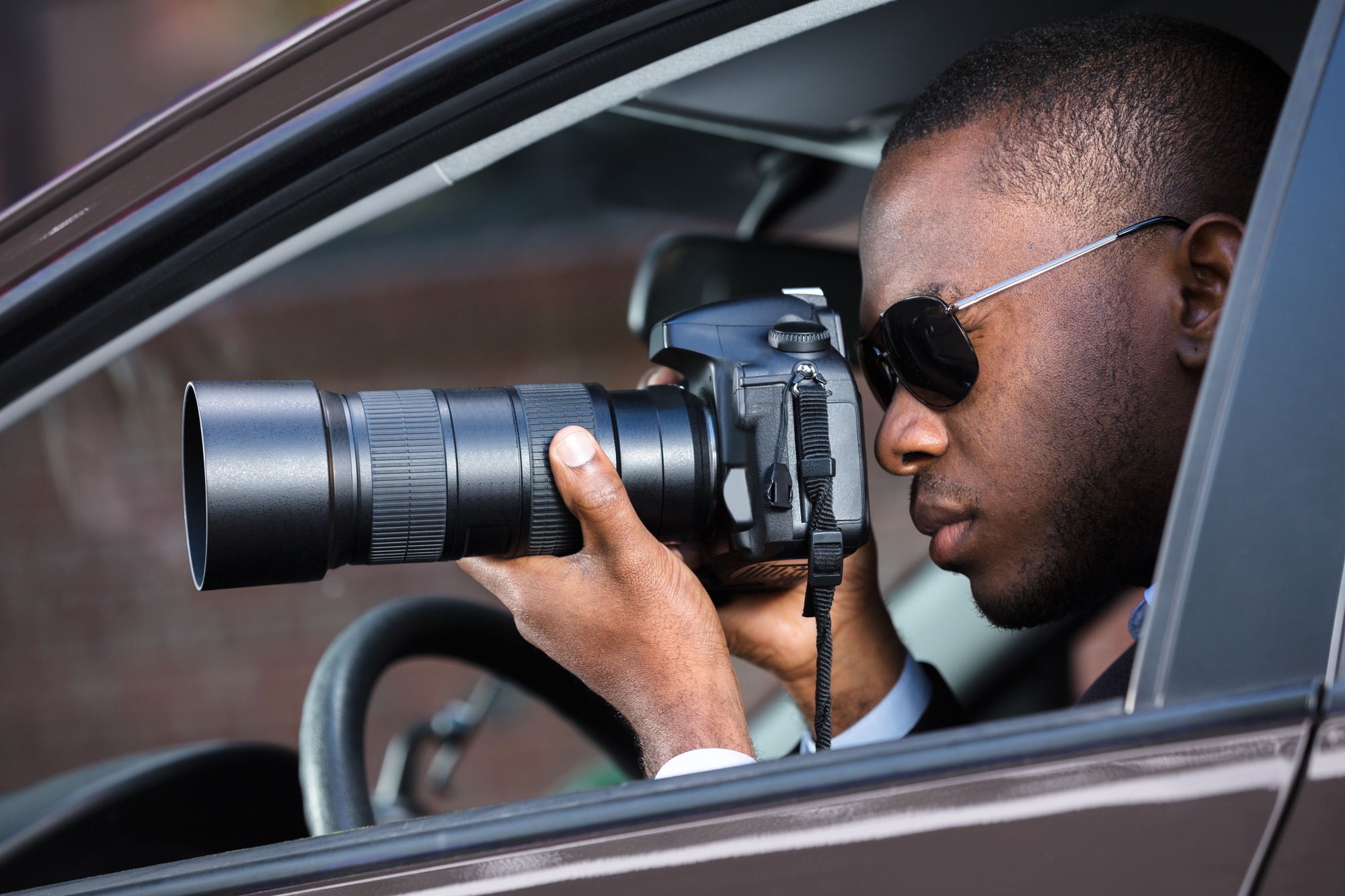 Private Detective Sitting Inside Car Photographing With Slr Camera